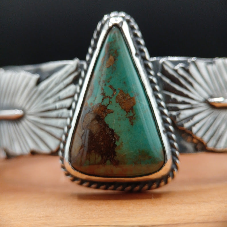 Turquoise stone ring with silver band on a wooden surface