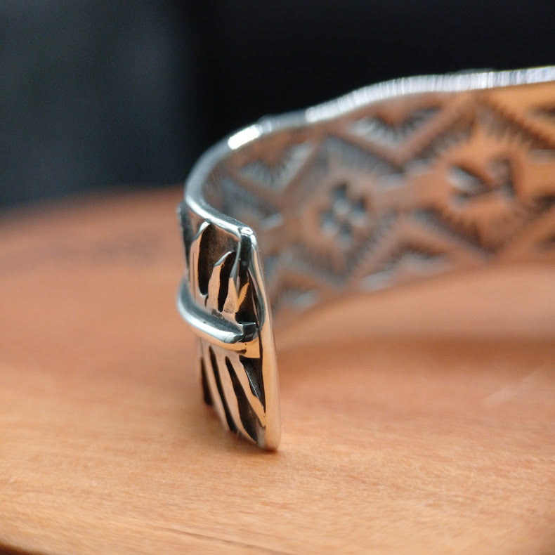 Silver bracelet with intricate design on a wooden surface