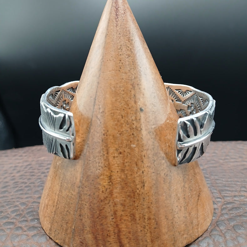 Silver ring with intricate design on a wooden stand against a dark background