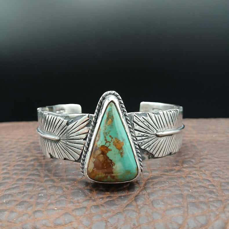 Silver bracelet with a large turquoise stone on a textured surface