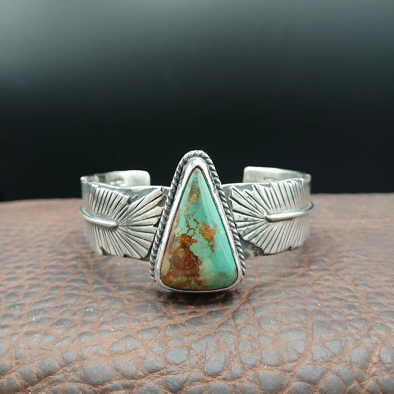 Silver bracelet with a turquoise stone on a textured surface
