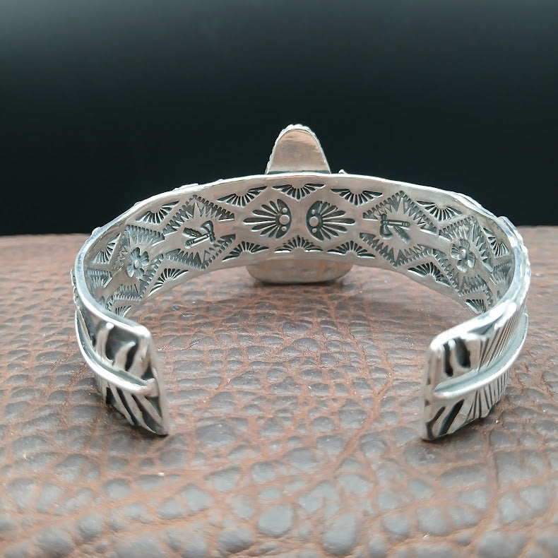 Silver bracelet with intricate designs on a textured surface