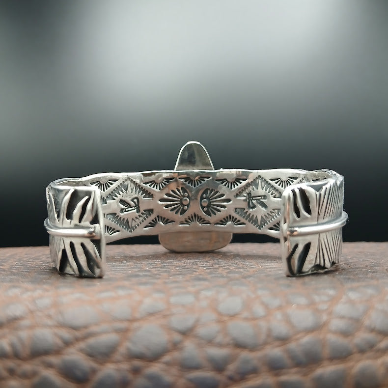 Silver bracelet with intricate patterns on a textured surface