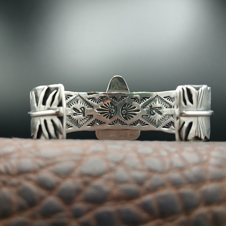 Silver bracelet with intricate designs on a textured surface