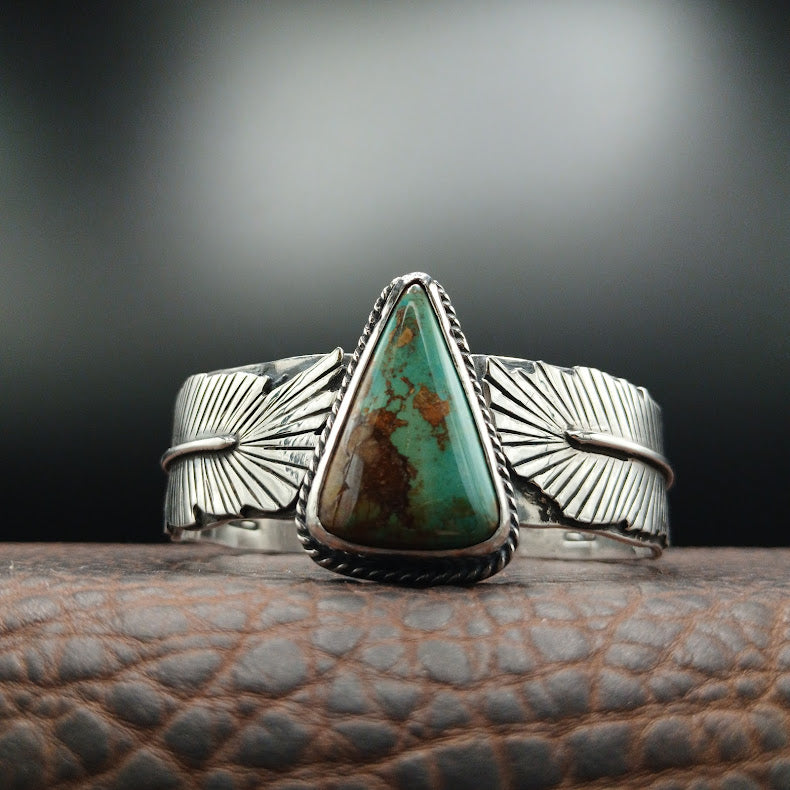 Silver ring with a large turquoise stone on a textured surface