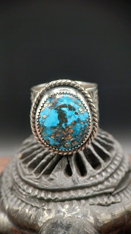 Turquoise ring with silver band on a dark background