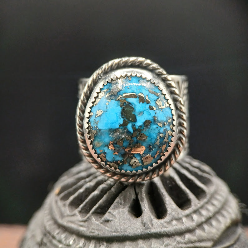 Silver ring with a blue stone on a textured surface