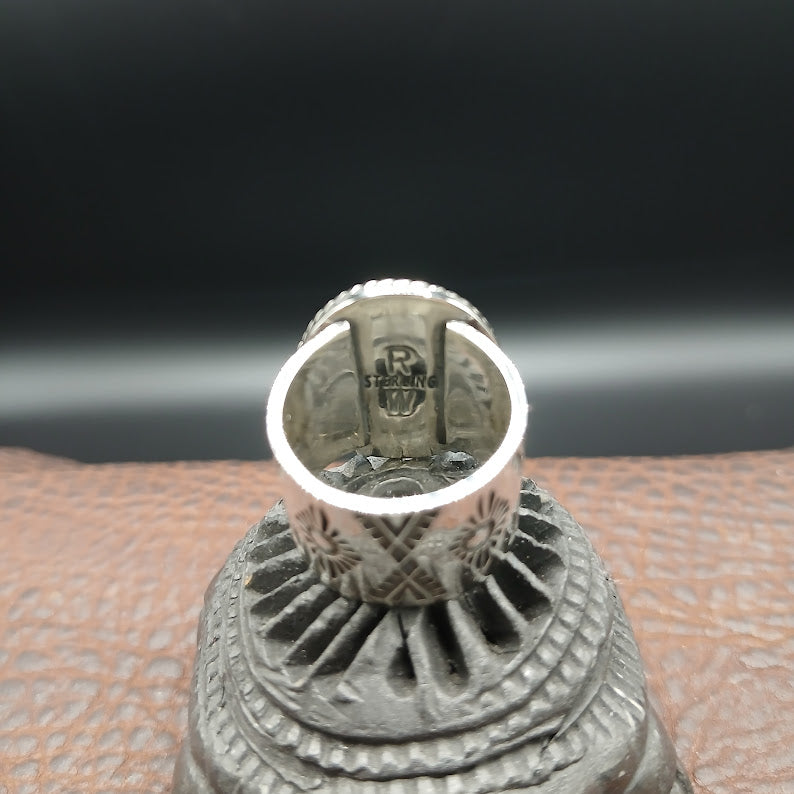 Close-up of a silver ring with RW and STERLING stamp on a textured surface