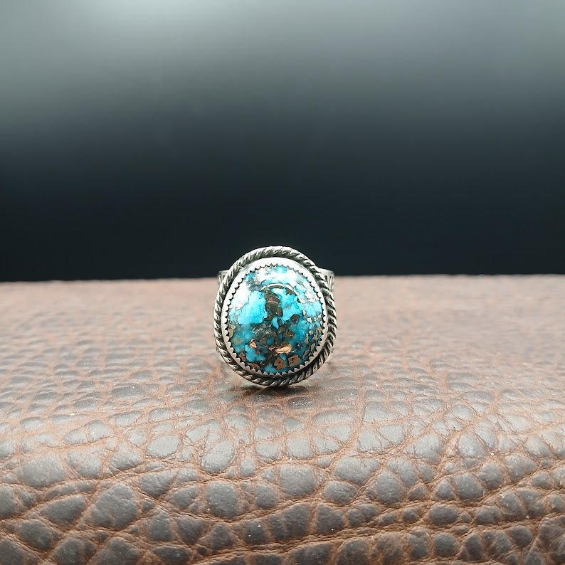 Silver ring with a turquoise stone on a textured brown surface