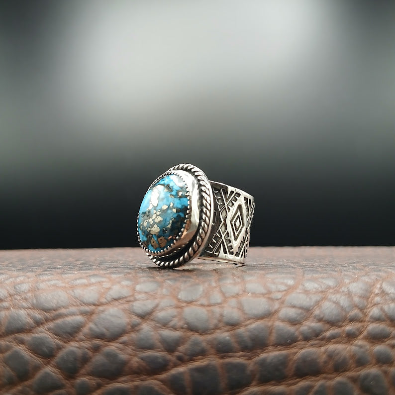 Silver ring with turquoise stone on a textured surface