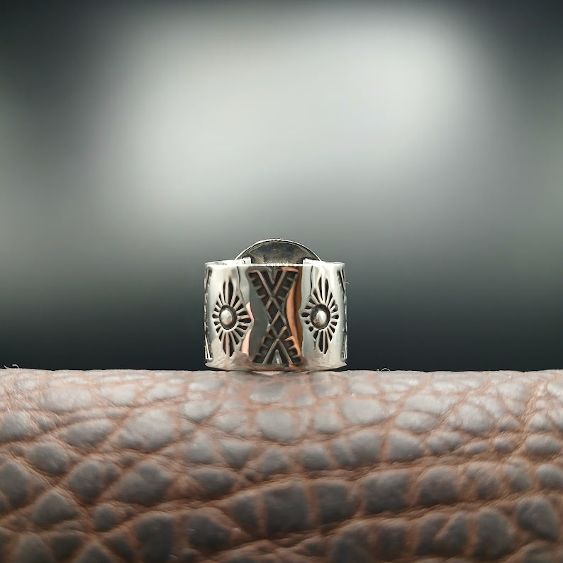 Silver ring with intricate designs on a textured surface