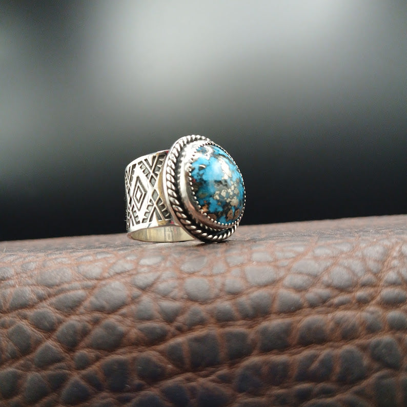 Silver ring with a blue stone on a textured surface