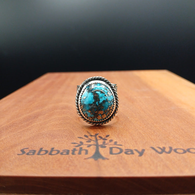 Turquoise stone ring on a wooden surface with 'Sabbath Day Wood' branding.