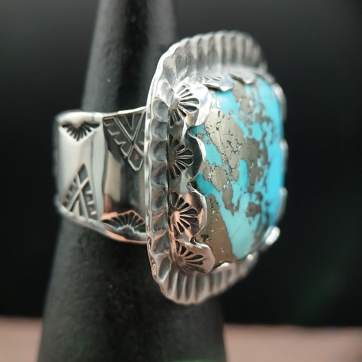 Hand-forged sterling silver turquoise ring face-on, natural turquoise cabochon with dark pyrite inclusions, leather surface