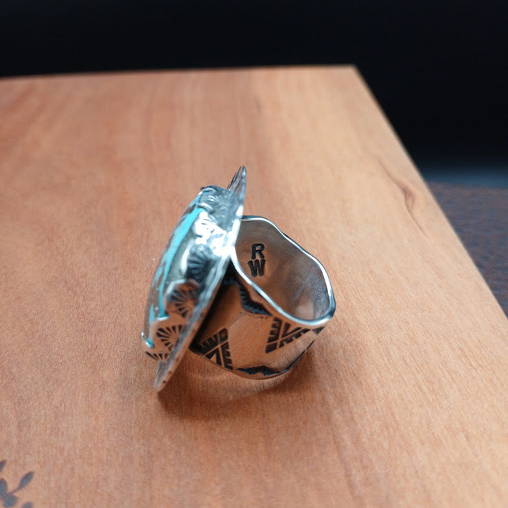 The Hardscrabble sterling silver turquoise ring, face-on view showing 35-carat natural turquoise with pyrite matrix in hand-serrated bezel, dark background