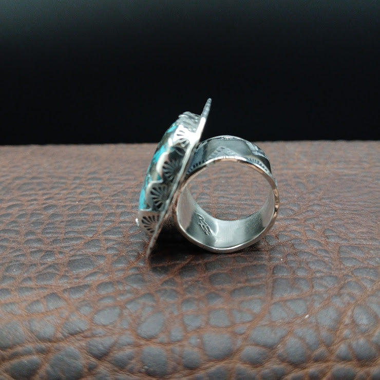 Close-up of RW hallmark and interior geometric stamp pattern on wide sterling silver band, leather surface