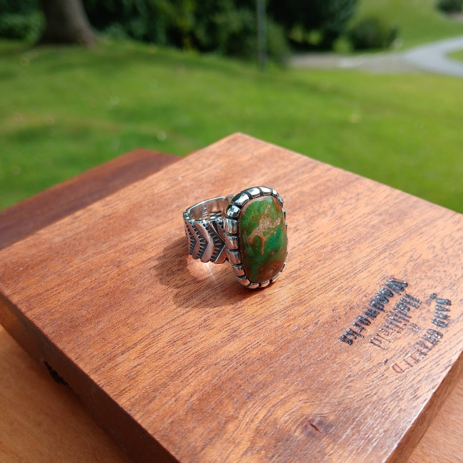 The Camelot — left profile, Sabbath Day Wood prop, dark background, vivid green stone